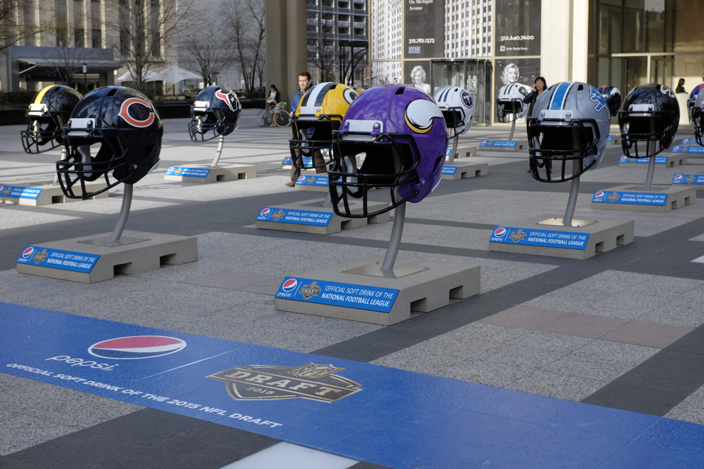 Giant NFL football helmets are displayed in Pioneer Court in downtown Chicago, as the city prepares to host the 2015 NFL Draft from April 30 to May 2. (AP Photo/Kiichiro Sato)