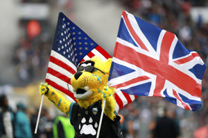 The Jacksonville Jaguars mascot runs on the Wembley Stadium field holding a USA and UK flag.