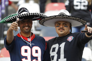 Two fans wearing sombreros pose together at an international NFL game.